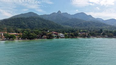 Turkuaz su, kumlu kıyılara, otellere ve tatil beldelerine uzanır. Bereketli tropikal bitkilerin arasına yerleşir. Malezya 'nın Tioman adasında, parlak mavi bir gökyüzünün altında görkemli dağlar tarafından desteklenir.