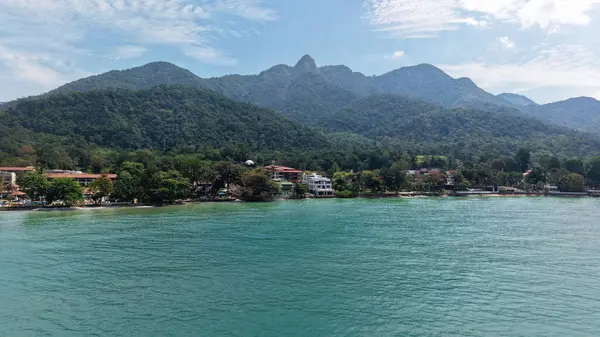 Turkuaz su, kumlu kıyılara, otellere ve tatil beldelerine uzanır. Bereketli tropikal bitkilerin arasına yerleşir. Malezya 'nın Tioman adasında, parlak mavi bir gökyüzünün altında görkemli dağlar tarafından desteklenir.