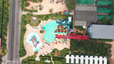 Yüksek slaytlı ve yüzme havuzlu bir su parkı. Tahttan parlak renkli slaytlara ve turkuaz su havuzuna kadar en üst manzara. İnsanlar yüzer, ata biner ve oynar. Her yerde ağaçlar ve palmiye ağaçları var.