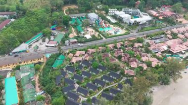 Geleneksel Tayland mimarisi, yemyeşil ve okyanusun davetkar turkuaz sularının sergilendiği el değmemiş bir sahil boyunca uzanan lüks bir tatil köyünün nefes kesici manzarası.