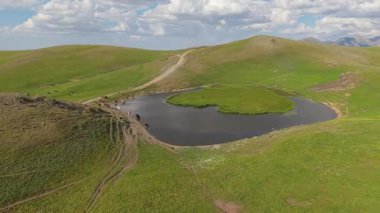Güzel kalp gölü yavaş yavaş suyla doluyor, yemyeşil tepeler ve dolambaçlı toprak bir yol ile çevrili, Artvin dağlarında sanatsal özellikler sergiliyor, hindi