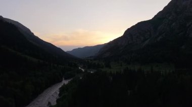 Güneş, dağ sırtının arkasında yavaşça batarken sıcak renkler gökyüzüne hakim oluyor. Titrek arkaplana karşı güzel bir siluet oluşturuyor.