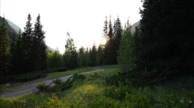 Yavaş yavaş dağların eteklerindeki çayırlarda kaybolan ışık, berrak güneş ışığından derinleşen alacakaranlığa huzurlu akşamları gözler önüne seriyor, doğal güzellikleri vurguluyor.