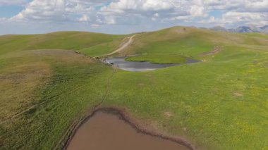 Güzel kalp gölü yavaş yavaş suyla doluyor, yemyeşil tepeler ve dolambaçlı toprak bir yol ile çevrili, Artvin dağlarında sanatsal özellikler sergiliyor, hindi