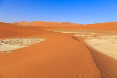 Kum tepesinden Sossusvlei 'nin tuz tepesine inanılmaz bir manzara. Namib Naukluft Ulusal Parkı. Sossusvlei 'deki kum tepeleri. Gün doğumu. Namibya. Afrika.