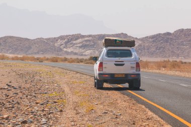 Sossusvlei, Namibya - 30 Eylül 2018: Namibya 'daki tipik 4x4 kiralık araba kamp malzemeleri ve Namibya çölünde toprak bir yolda yol alan bir çatı çadırıyla donatılmış..