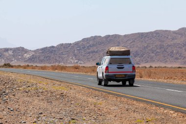 Sossusvlei, Namibya - 30 Eylül 2018: Namibya 'daki tipik 4x4 kiralık araba kamp malzemeleri ve Namibya çölünde toprak bir yolda yol alan bir çatı çadırıyla donatılmış..