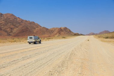 Sesriem, Naukluft, Namibya - 01 Ekim 2018: Namibya 'daki tipik 4x4 kiralık araba kamp malzemeleri ve Namibya çöllerinde toprak bir yolda ilerleyen bir çatı çadırı.