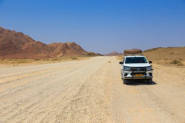 Sesriem, Naukluft, Namibya - 01 Ekim 2018: Namibya 'daki tipik 4x4 kiralık araba kamp malzemeleri ve Namibya çöllerinde toprak bir yolda ilerleyen bir çatı çadırı.