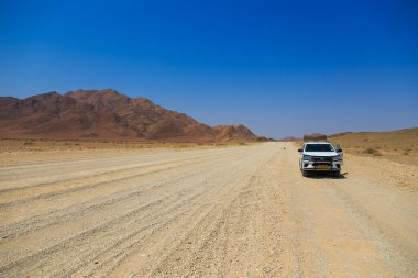 Sesriem, Naukluft, Namibya - 01 Ekim 2018: Namibya 'daki tipik 4x4 kiralık araba kamp malzemeleri ve Namibya çöllerinde toprak bir yolda ilerleyen bir çatı çadırı.