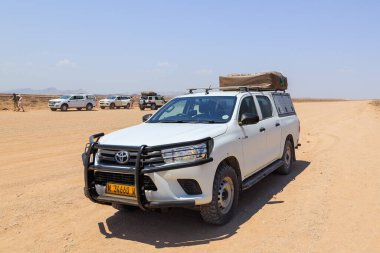 Khomas Bölgesi Oğlak, Namibya - 02 Ekim 2018: Namibya 'daki tipik 4x4 kiralık araba kamp malzemeleri ve Namibya çölünde toprak bir yolda ilerleyen bir çatı çadırı.