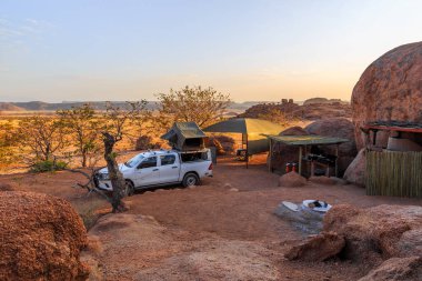 Mowani, Damaraland, Namibya - 04 Ekim 2018: Namibya 'da kamp malzemeleri ve kamp alanında bir çatı çadırıyla donatılmış tipik 4x4 kiralık araba.