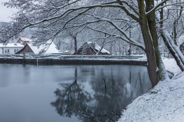 Polonya, Gdansk, Oliwa - 16 Aralık 2018: Karlı Eğlence Vadisi manzarası. Tarihi Old Mill 'in yanında bir gölet.