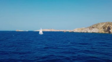 Chora, Ios Adası, Yunanistan - 26 Eylül 2020: yelkenli Chora limanından kalkıyor. Arka planda tepeler.