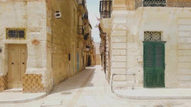 Birgu, Malta - 21 Haziran 2021: Malta 'da güneşli bir günde Birgu' da bir sokakta yürümek. Arabalar park yerinde. Eski bina ve dar sokak.