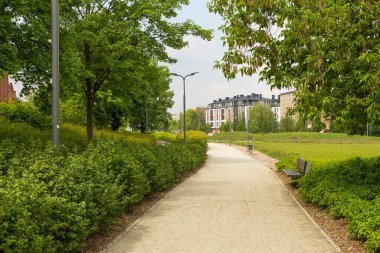 Bahçesinde bank olan bir yol. Arkaplanda yeni apartman bloğu.