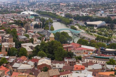 Tiflis, Gürcistan - 30 Ağustos 2019: Teleferiğin eski Tiflis manzarası: Barış Köprüsü, Konser Müzik Tiyatrosu ve Sergi Salonu, Tiflis 'in kalbinden Kura Nehri' ni geçen Ortodoks kilisesi.