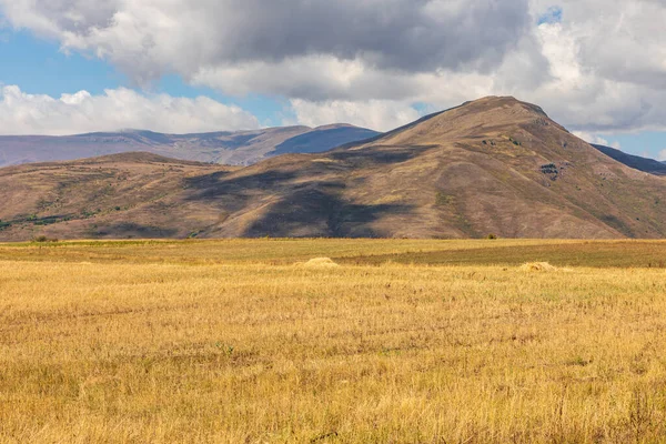 Landscape of the Armenian Caucasus mountains. Yellow-gold grass, wilde land and blue sky. Endless fields. Armenia.