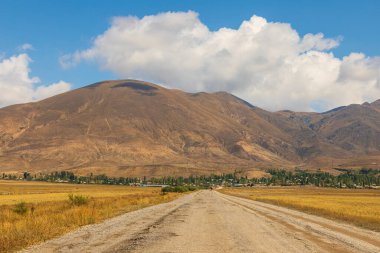 Truck on the gravel road. The Caucasus Mountains in the background.Sevan, Armenia. clipart