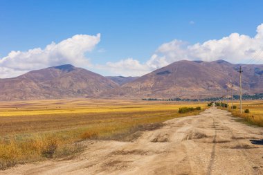 Truck on the gravel road. The Caucasus Mountains in the background.Sevan, Armenia. clipart