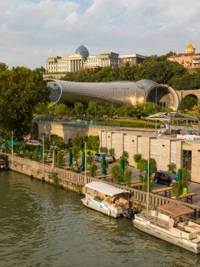Tiflis, Gürcistan - 06 Eylül 2019: Eski Tiflis kasabasındaki Kura (Mtkvari) nehrinin manzarası. Tören Sarayı, bir tepenin üstünde Gürcistan Başkanı 'nın evi..