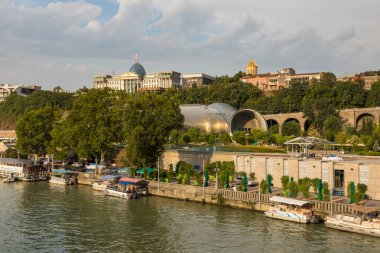 Tiflis, Gürcistan - 06 Eylül 2019: Eski Tiflis kasabasındaki Kura (Mtkvari) nehrinin manzarası. Tören Sarayı, bir tepenin üstünde Gürcistan Başkanı 'nın evi..