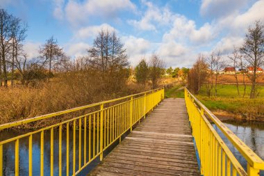 Radunia Nehri üzerindeki küçük sarı köprü. Arka planda orman var. Kashubia, Pomerania, Polonya.