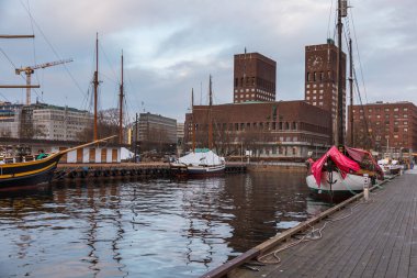 Oslo, Norveç - 07 Ocak 2020: Yat ve tekneler Oslo 'da limana demir attı. Arkaplanda tarihi Oslo Belediye Binası. Norveç 'in başkenti..