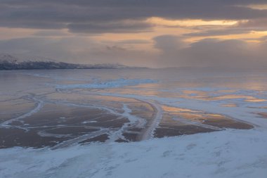 Sunset over Lake Tornetrask. The lake is covered in ice. Winters season. Bjorkliden, Lapland, Sweden.