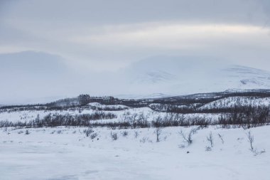 Frozen Lake Tornetrask. Cloudy winter day. Mountains in the background. Abisko, Lapland, Sweden.