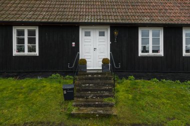Kivik, İsveç - 07 Mart 2020: İsveç 'in güneyinde küçük bir kasabada beyaz kapılı ve panjurlu geleneksel siyah ahşap ev. Neden?