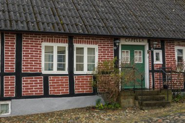 Kivik, İsveç - 07 Mart 2020: İsveç 'in güneyindeki küçük bir kasabada geleneksel yarı keresteli ev. Yeşil kapılı kırmızı tuğla bina.