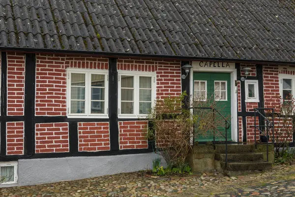 Kivik, İsveç - 07 Mart 2020: İsveç 'in güneyindeki küçük bir kasabada geleneksel yarı keresteli ev. Yeşil kapılı kırmızı tuğla bina.