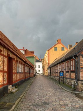İsveç 'in Ystad şehrinde güneş ışığıyla aydınlatılan geleneksel tuğla evler ve kaldırımlı yaya sokakları. Tarihi kasaba görünümü.