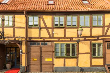 Ystad, İsveç - 7 Mart 2020: Kereste çerçeveli geleneksel otel binası, yeşil pencereli ve girişte İsveç bayrağı.