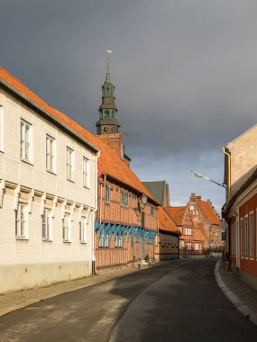 Ystad, İsveç - 7 Mart 2020: Yarı ahşap binalı cadde ve tarihi kent merkezinde St. Mary Kilisesi kulesi.