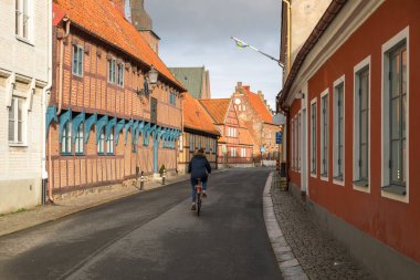 Ystad, İsveç - 7 Mart 2020: Yarı ahşap binalı cadde ve tarihi kent merkezinde St. Mary Kilisesi kulesi.