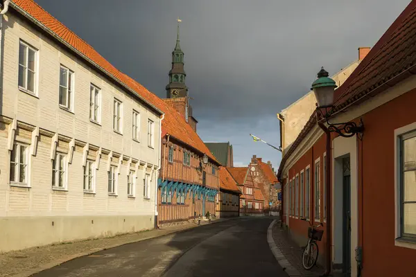 Ystad, İsveç - 7 Mart 2020: Yarı ahşap binalı cadde ve tarihi kent merkezinde St. Mary Kilisesi kulesi.