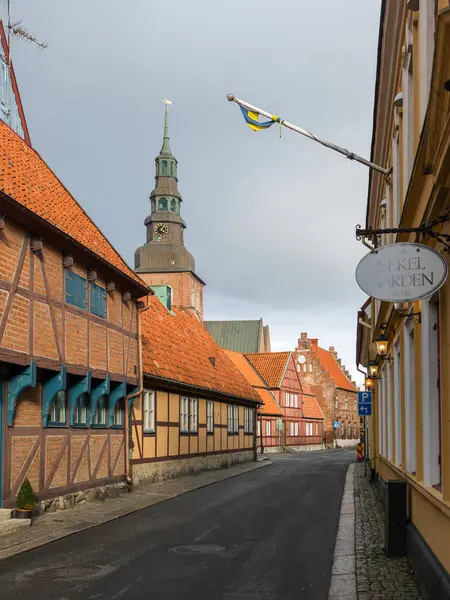 Ystad, İsveç - 7 Mart 2020: Yarı ahşap binalı cadde ve tarihi kent merkezinde St. Mary Kilisesi kulesi.