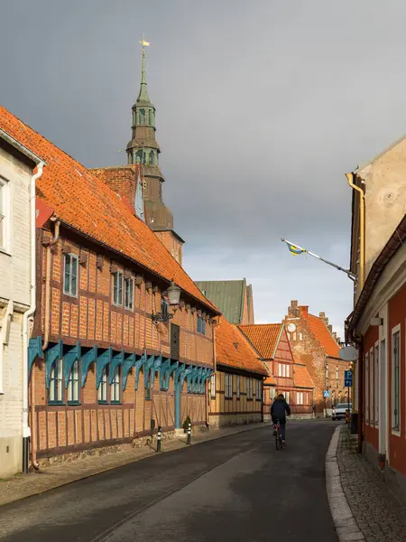 Ystad, İsveç - 7 Mart 2020: Yarı ahşap binalı cadde ve tarihi kent merkezinde St. Mary Kilisesi kulesi.