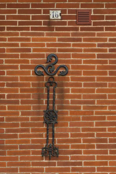 Süslü siyah demirler kırmızı tuğla duvara monte edilmiş. Ystad, İsveç 'te 16 numara..