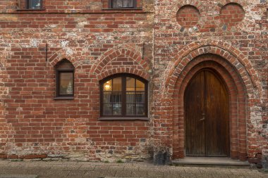 Ystad, İsveç 'te kemerli kapı ve küçük pencereli tarihi tuğla cephesi. Ortaçağ mimari detayları.