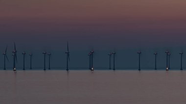 İsveç 'in Malmö yakınlarındaki Oresund Boğazı' ndaki açık deniz rüzgâr çiftliği, gün batımında sıcak tonlarda yakalandı..