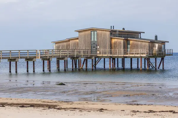 İsveç 'in Torekov sahilinde tahta ayaklıklar üzerinde ahşap sahil hamamı. Bulutlu gökyüzü ve alçak gelgitle sakin bir gün.
