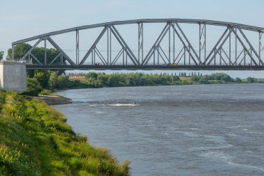 Çelik bir demiryolu köprüsü Polonya 'nın Tczew kentindeki Vistula Nehri' ni kapsar. Güneşli bir yaz gününün altından bir jet ski geçiyor.