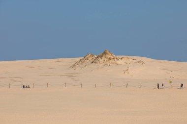 Leba, Polonya 12 Eylül 2020: Turistler Slowinski Ulusal Parkı 'ndaki kum tepeleri yakınında çitli bir patika boyunca yürüyorlar.