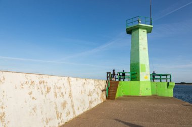 Wladyslawowo, Polonya 13 Eylül 2020: Baltık Denizi kıyılarında beton tetrapodlarla kaplı eğri dalgalı su boyunca yürüyen ziyaretçiler.