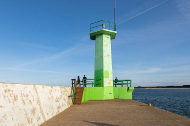 Wladyslawowo, Polonya 13 Eylül 2020: Baltık Denizi kıyılarında beton tetrapodlarla kaplı eğri dalgalı su boyunca yürüyen ziyaretçiler.