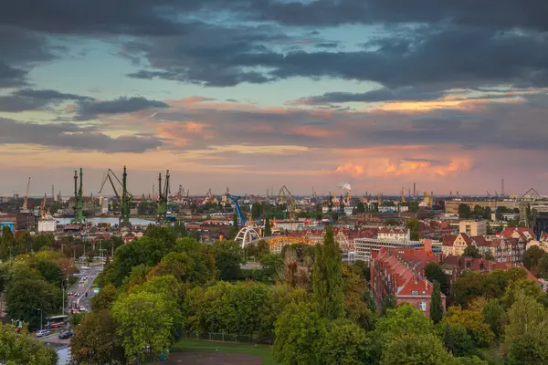 Gdansk, Polonya 7 Ekim 2020: Tersane vinçleri, duman yığınları ve kırmızı çatılı apartman binaları ile Gdansk 'ın sanayi manzarası.