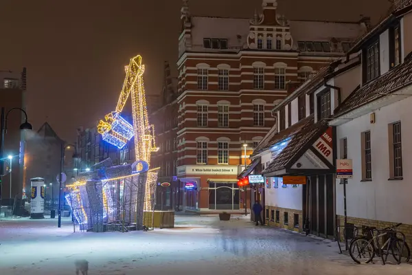 Gdansk, Polonya 8 Şubat 2021: İnsanlar kar yağışı sırasında Long Market boyunca yürürken, Main Town Hall geceleri aydınlanıyor.